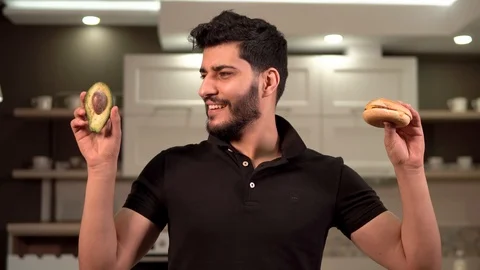 Man Hesitates between Avocado and Hamburger 動画素材 87284107