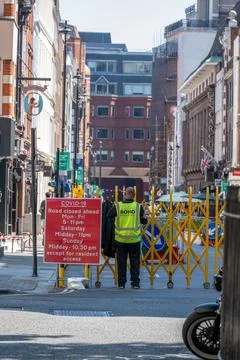 A man in a hi-vis jacket stood next to a COVID-19 sign enforcing coronavirus Stock Photos