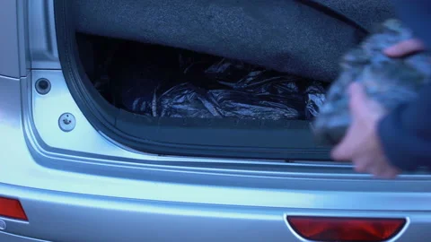 Man hiding forbidden packets in car trunk, drugs smuggling, illegal trading Video stock 94671700