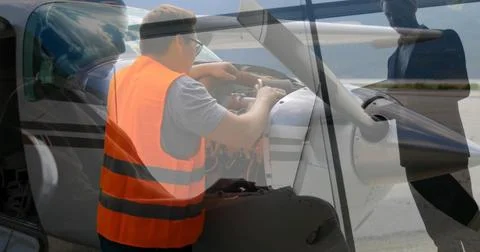 Man in high-vis vest checking engine through open cowling on apron, with crew Stock Photos