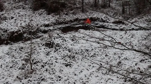 Man in high-viz jacket cycling down snowy forest path Stock Footage 83409470
