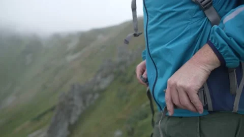 A man on a hike puts on a backpack and fastens his belt, close-up Stock Footage 231245389