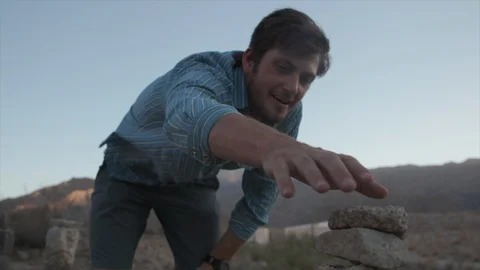 Man on Hike Stacking Rocks in Desert Mountains Stock Footage 95932319