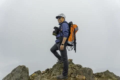 Man hiker with backpack in front of a mountain Stock Photos