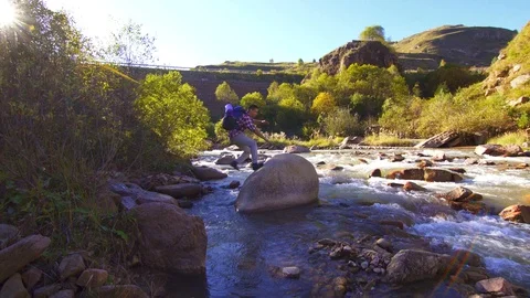 Man hiker with backpack on a mountain river rejoices Stock-Footage 95548843