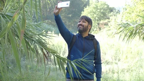 Man hiker with a beard and backpack in the middle of nature taking a selfie Stock Footage 139615270