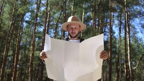 Man hiker consults a map in the forest. Composition hiking. Video stock 149945719