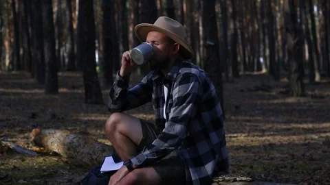 Man hiker drinks tea during a halt in the forest. Concept hike, tourism. Stock Footage 150255551