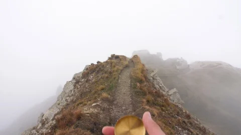 Man hiker hands with compass on mountain with cloudy sky and fog. Yellow jacket 스톡 동영상 122104492