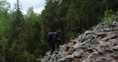 A man is a hiker on a hike in a mountain forest walking on rocky Stock Footage 243738711