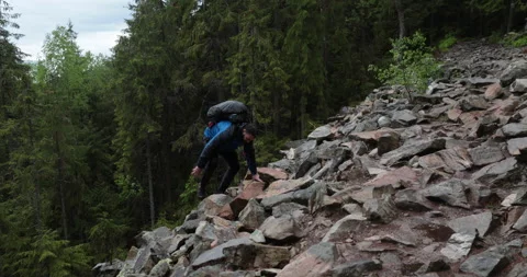 A man is a hiker on a hike in a mountain forest walking on rocky Stock Footage 243739493