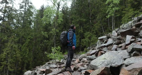 A man is a hiker on a hike in a mountain forest walking on rocky Stock Footage 243740384