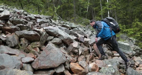 A man is a hiker on a hike in a mountain forest walking on rocky Stock Footage 243742309