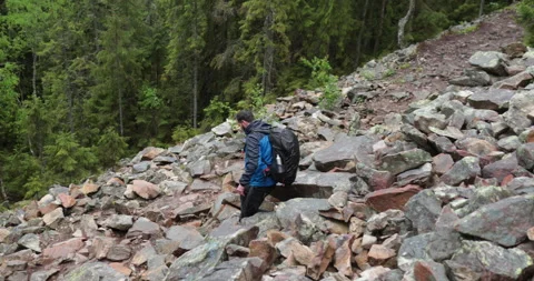 A man is a hiker on a hike in a mountain forest walking on rocky Stock Footage 243745074