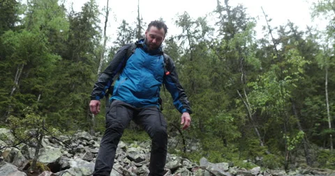 A man is a hiker on a hike in a mountain forest walking on rocky Stock Footage 243747506