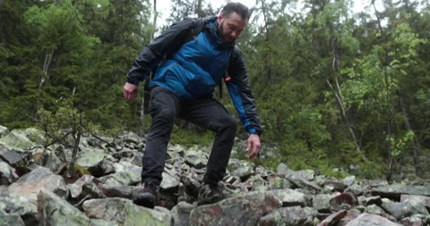 A man is a hiker on a hike in a mountain forest walking on rocky Stock Footage 243748314