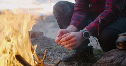 Man hiker make fire in forest. Warms up by the fire. Camping Stock Footage 128527125
