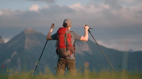 Man hiker red backpack standing on hill top raised hands with trekking poles Stock Footage 283500869