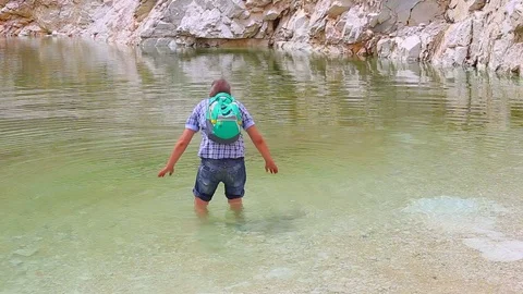 Man hiker refreshing at some large abandoned marble quarry pond Stock Footage 108656851