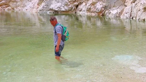 Man hiker refreshing at some large abandoned marble quarry pond Stock Footage 108657660