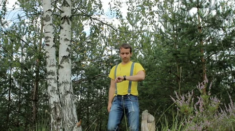 Man hiker walking through the forest and touch smart watch. Yellow T-shirt and Stock Footage 66269500