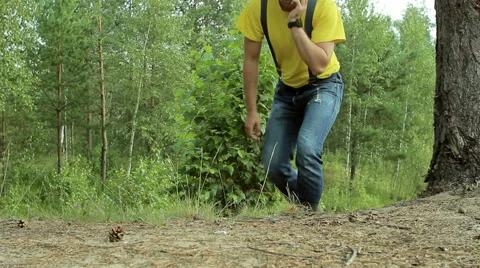 Man hiker walking through the forest and talking on the phone. Yellow T-shirt Stock Footage 66271135