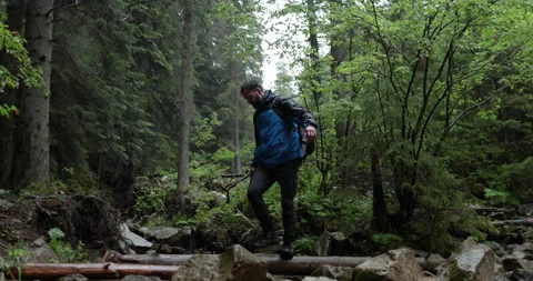 A man hiker walks through a mountain stream in the forest Stockbeeldmateriaal 243722178