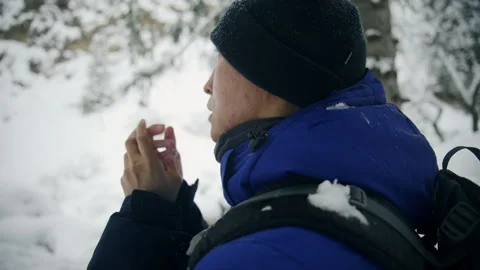 Man hiker warming hands in snowy forest during winter adventure with backpack Stock Footage 341337774