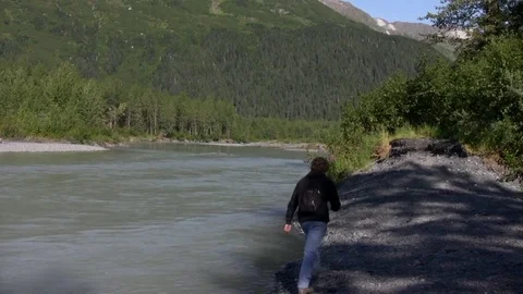 Man hikes edge of small river in Alaska Stock Footage 78974285
