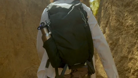 Man hiking with a backpack on a well worn mountain trail with high walls Stock Footage 87743502