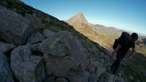 A man hiking up a mountain and checking his watch with Tryfan Stock Footage 161794149