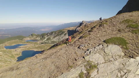 Man hiking at mountains with heavy backpack. Seven Rila Lakes in the background Stock Footage 220842073