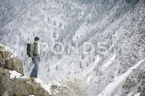 A man hiking in the mountains standing looking into a valley. Stock Photos