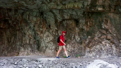 Man hiking in mountains, walking through tunnel cut in rock Stock Footage 159773496