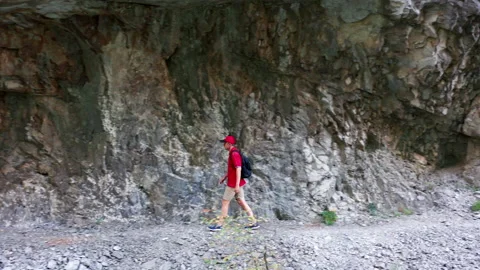 Man hiking in mountains, walking through tunnel cut in rock Stock-Footage 159847572