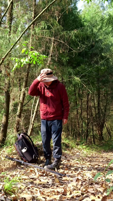 A man hiking stops for a short rest because he’s too hot from the exercise. Stock Footage 329551893