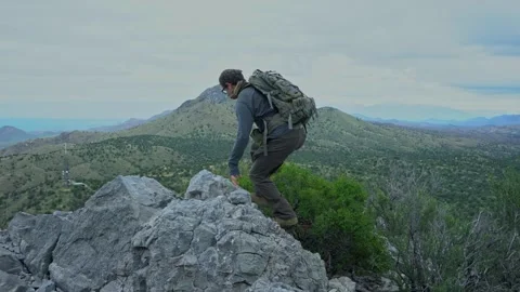 A man hiking to the summit of a rugged mountain Stock Footage 316487868