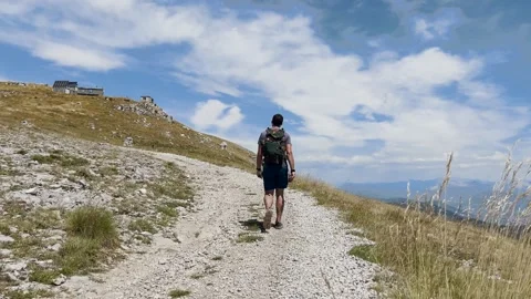 Man Hiking Toward Mountain Summit on Trail, Ground Level View Stock Footage 338007266