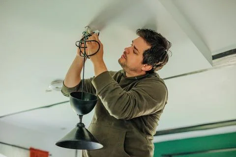 Man himself repaired lamp on the ceiling in the kitchen at home Stock Photos