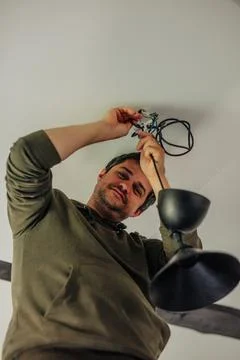 Man himself repaired lamp on the ceiling in the kitchen at home Stock Photos