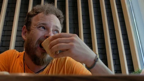 Man hipster with a beard eating pizza at a cafe and thoroughly chewing.4k. Видео 111383455