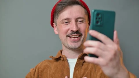 A man in his 30s with light skin and a mustache interacts with his smartphone, Видео 337643195