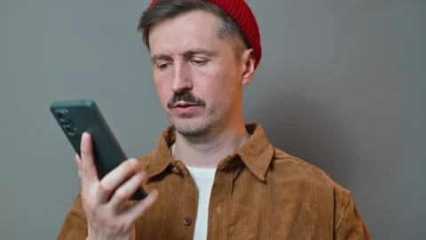 A man in his 30s with light skin and a mustache is using a smartphone while Stock Footage 337643265
