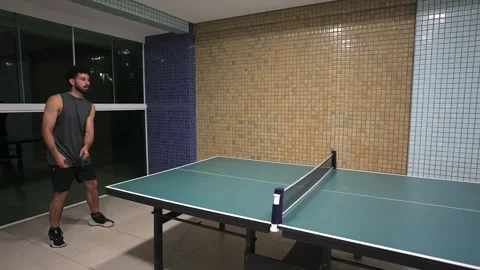 Man in his 30s playing a game of table tennis or ping pong in a recreation room Stock Footage 317757385