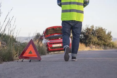 Man with his back to the camera puts a warning triangle behind his car Stock Photos