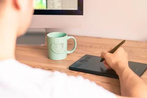 Man with his back to the tablet sitting in front of the computer and working Stock Photos