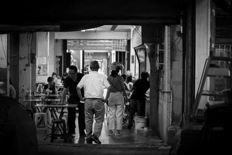A man with his back walking through a food stand at arcade in Tainan street. Stockfoto's