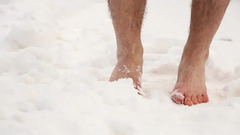 The man with his bare feet trying to warm up somehow on cold snow Stock Footage 88586405