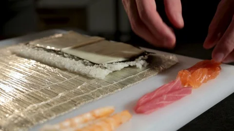 A man with his bare hands puts the salmon on the cheese. Japanese rolls. 스톡 동영상 87012334