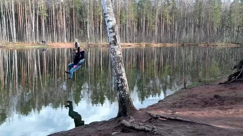 Man with his daughter on his back rides a homemade bungee. Above the lake in the Stock Footage 192483592
